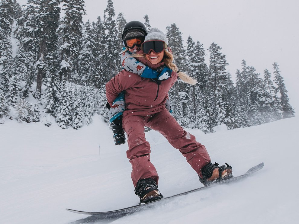 Burton Ambassador Kate Ediger snowboarding with her son on her back