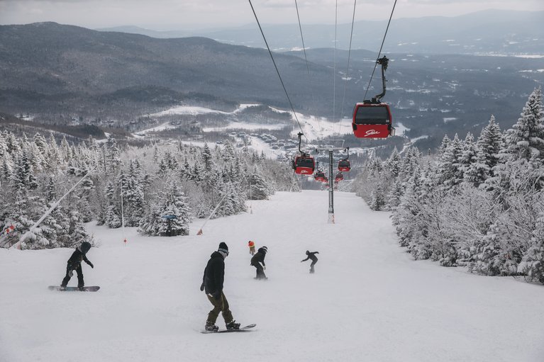 Snowboarders ride under the gondola at Stowe Mountain Resort