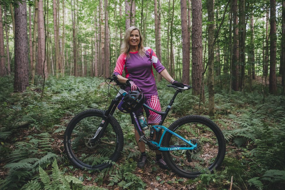 Elysa Walk standing next to her bike in the woods.