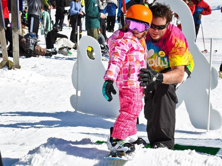 Emmet Manning teaching a young girl to snowboard.