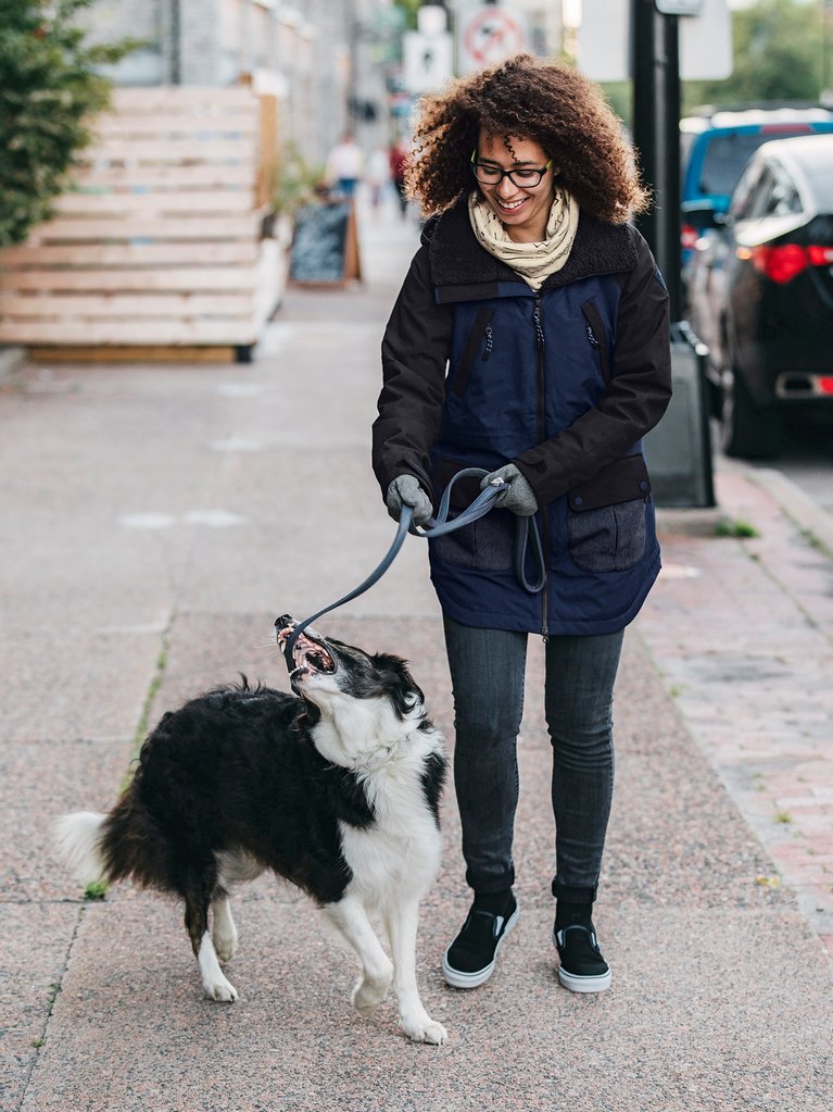 A woman wearing a Burton Prowess jacket walking her dog.