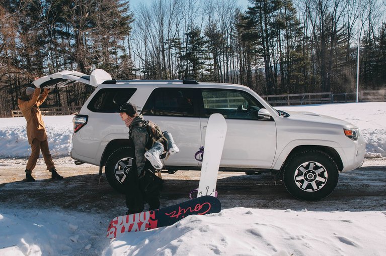 A group of women loading snowboards into a Toyota 4Runner