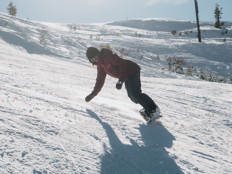 1) Luta överkroppen och din kroppsvikt över nosen på din snowboard tills båda händerna ligger på snön ungefär i axelbredd i en handstandsliknande position. Majoriteten av din vikt ska stödjas av händerna och armarna och inte av din snowboard.